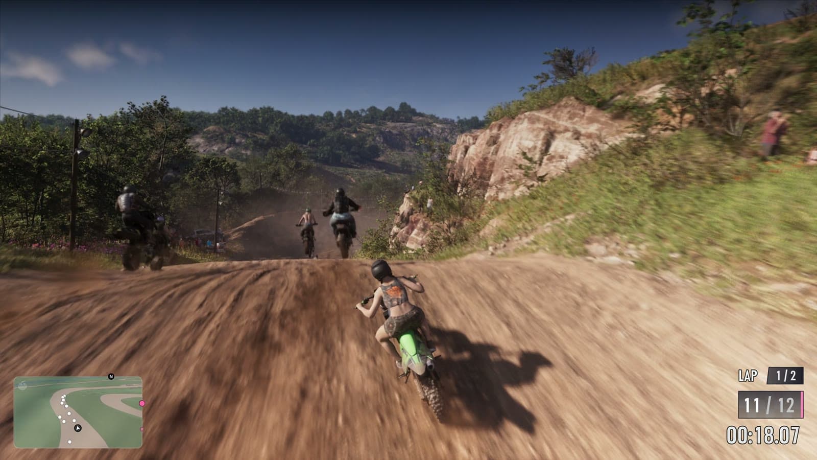 Course de motos sur une piste de terre entre des talus rocheux, avec tours, position et chronomètre